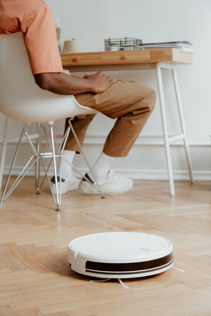 man sitting behind desk and cleaning robot on floor